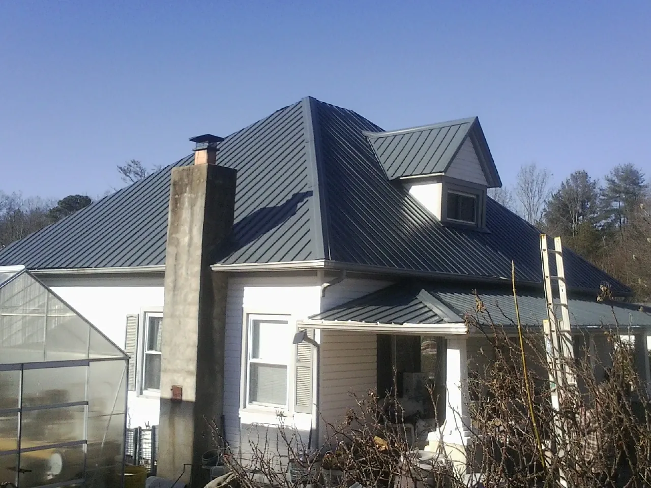Dark blue standing seam metal roof on a white farmhouse with dormer — Slate & Tile Roof Repair by Roofing Brothers in West Valley City