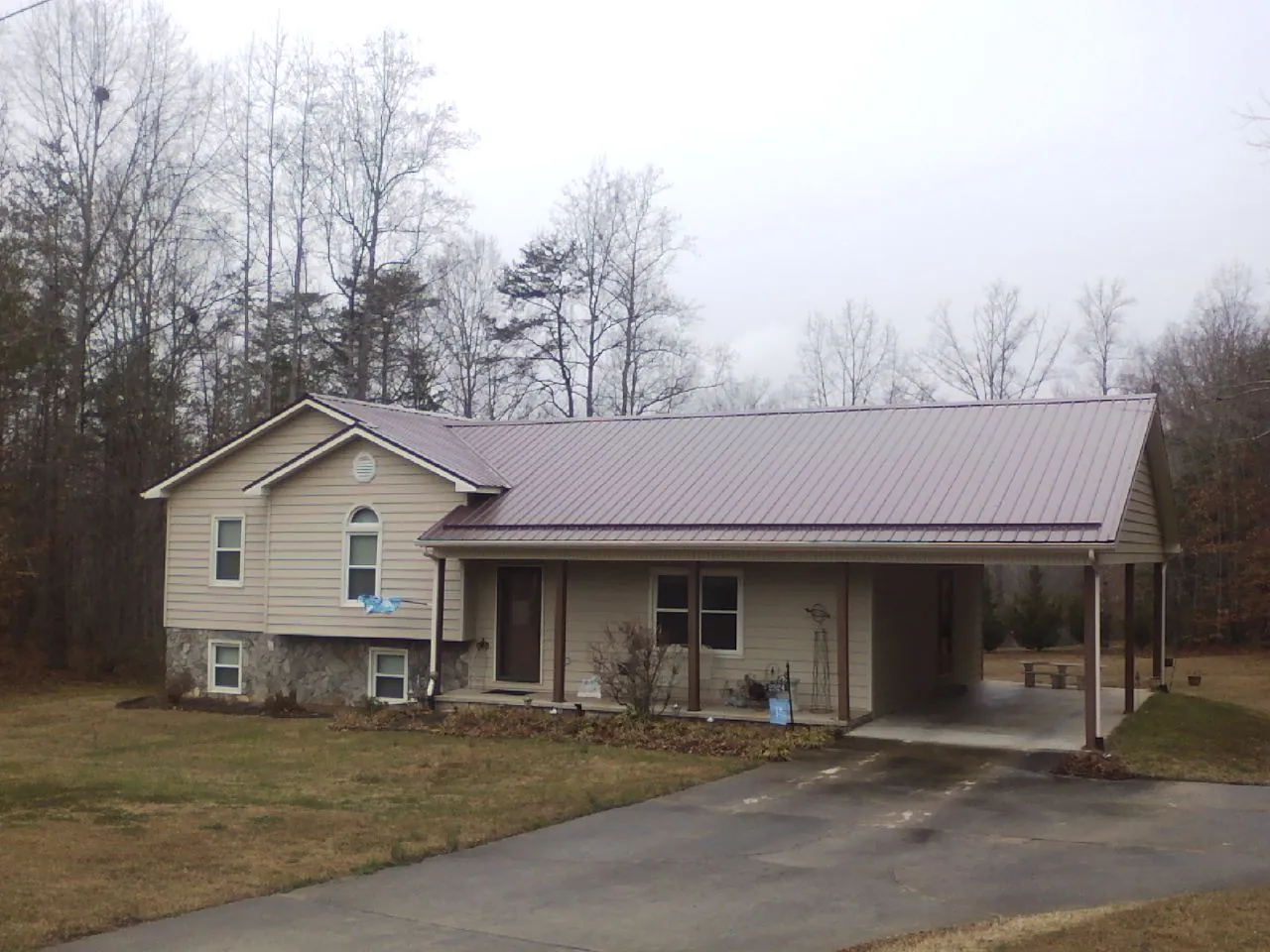 Burgundy metal roof on a tan split level home with an attached carport in West Valley City