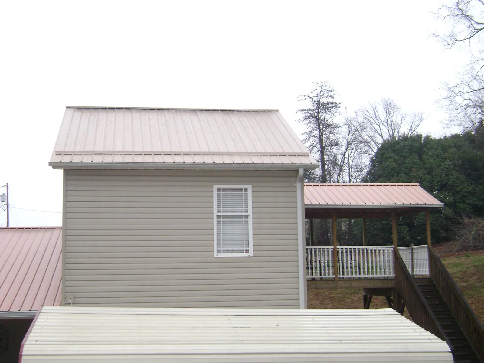 Tan metal roofs on a two story addition and attached porch, from a Roof Replacement job in West Valley City