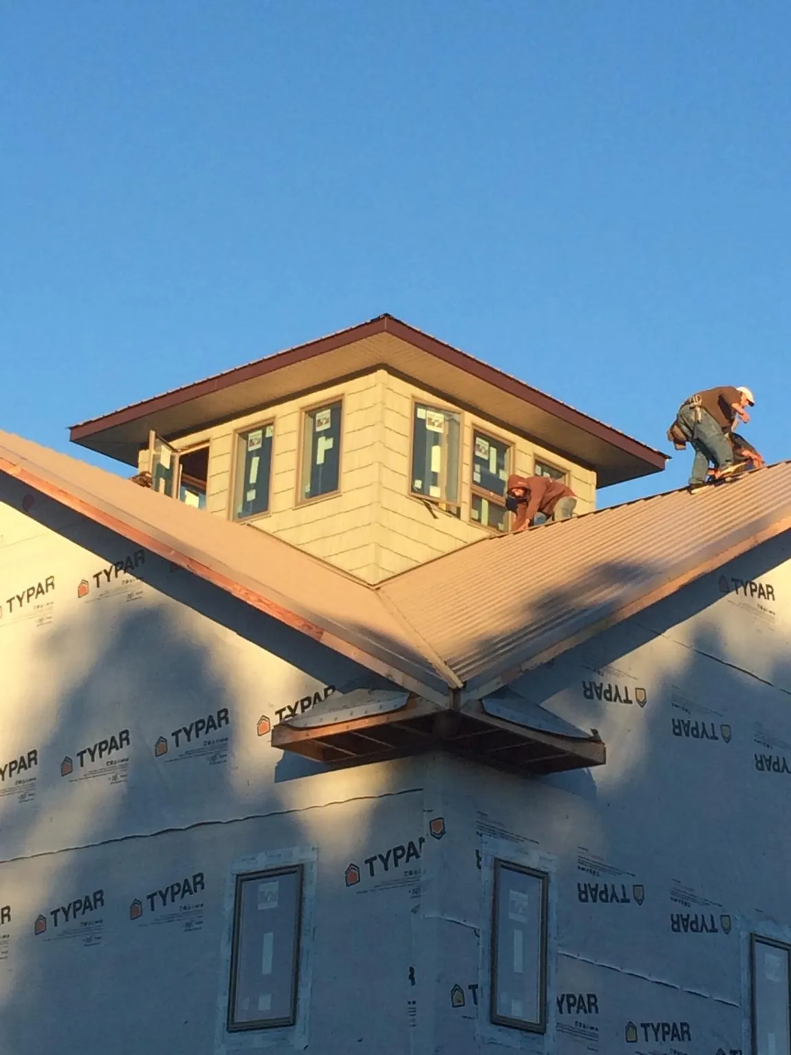 Roofers working around a rooftop cupola on a new metal roof at sunset — Roof Waterproofing in West Valley City by Roofing Brothers